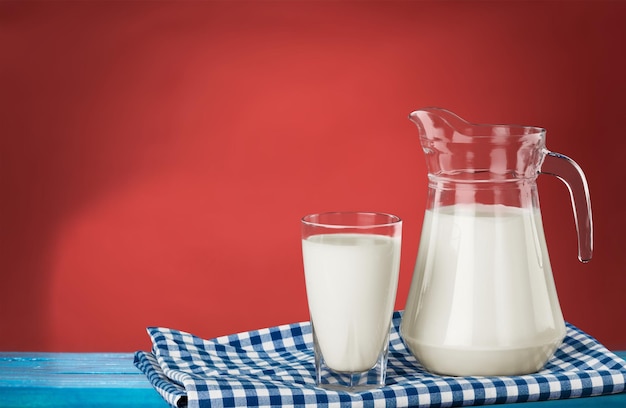 Kruik en glas met melk op een houten tafel.