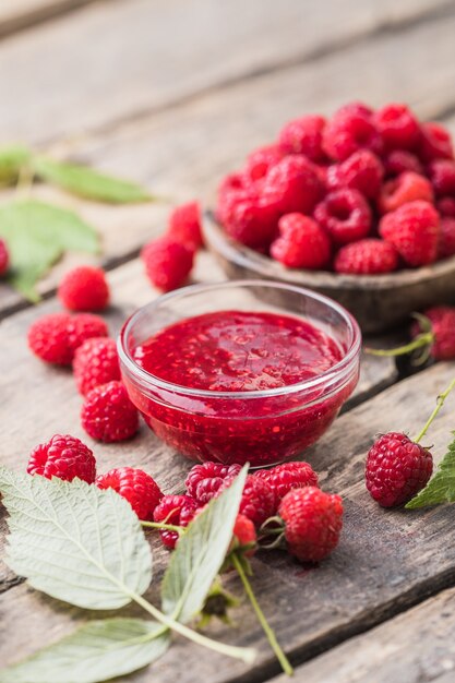 Kruik frambozenjam en verse bessen met bladeren. Zoet dessert