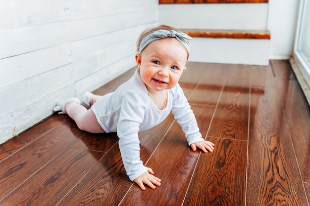 Kruipende babymeisje op verdieping in helder licht woonkamer glimlachen en lachen