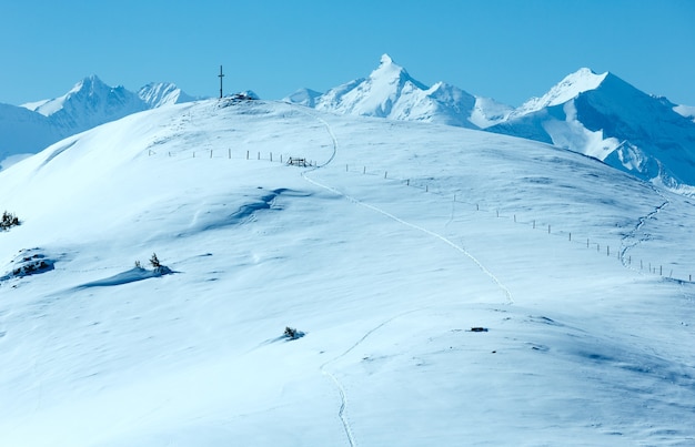 Kruis op winterberg Shneeberg top en bekijk Alpenpieken erachter (Hochkoenig-regio, Oostenrijk)