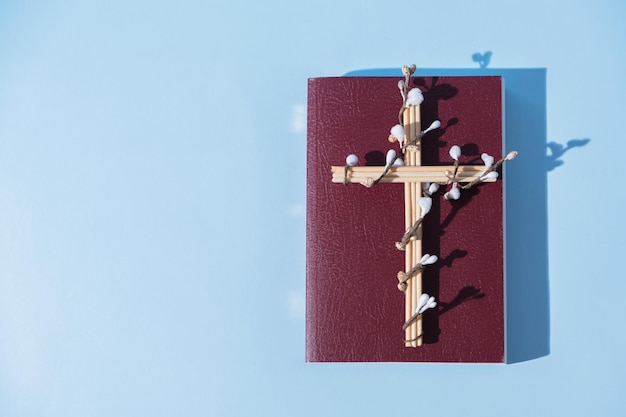 Kruis versierde bloemen met Heilige Bijbel op blauwe achtergrond Paasvakantie minimalistisch concept