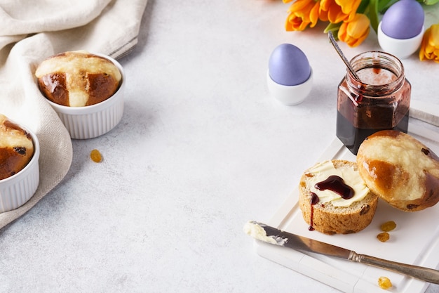 Kruisbroodjes, boter, jam en gekleurde eieren voor het paasontbijt.