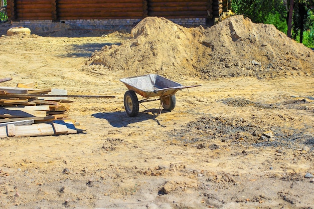 Kruiwagen op de werf tussen het zand en planken