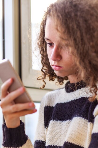 Krullend haar tienermeisje met behulp van mobiele telefoon