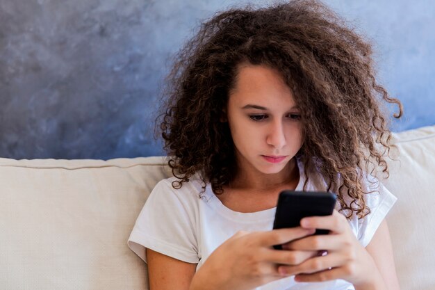 Krullend haar tienermeisje schrijft sms-berichten