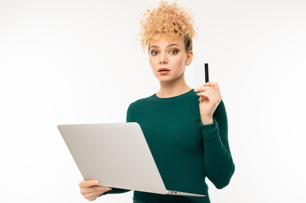 Krullend meisje dat laptop in haar handen op wit houdt