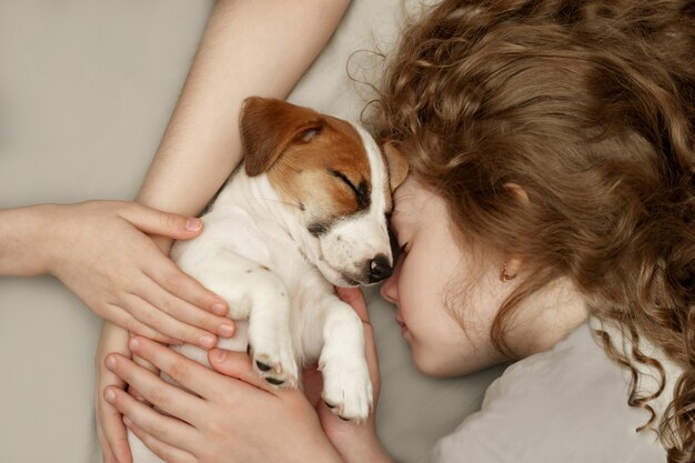 Krullend meisje en de handen van de kinderen knuffelen een puppy