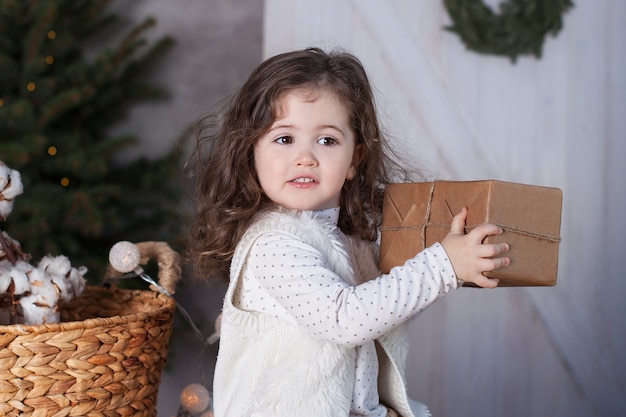 Krullend meisje opent een geschenk met Kerstmis.