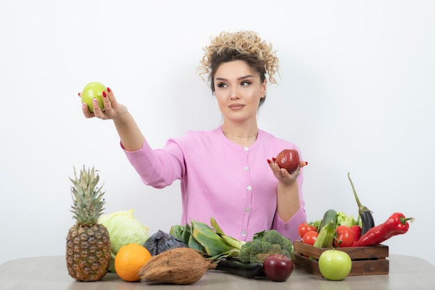 Krullend vrouw zittend aan tafel met heerlijk fruit.