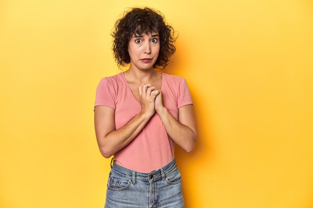 Foto krullende blanke vrouw in roze t-shirt bang en bang.