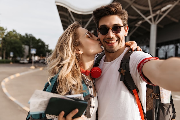 Krullende blonde vrouw kust vriendje in zonnebril