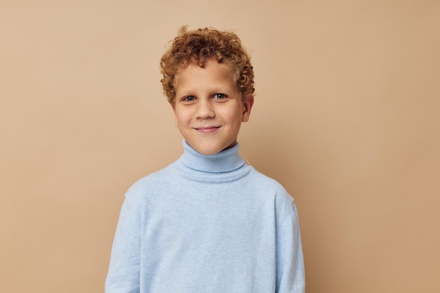 Krullende jongen in een blauwe trui poseren leuke kinderjaren ongewijzigd