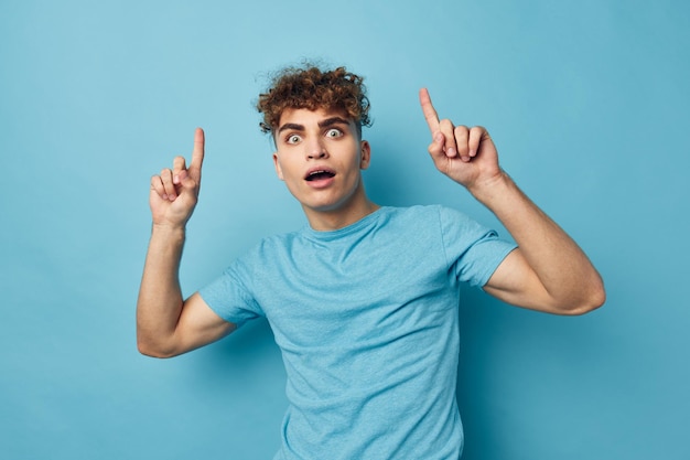 Krullende man in een t-shirt op een gekleurde achtergrond poseren