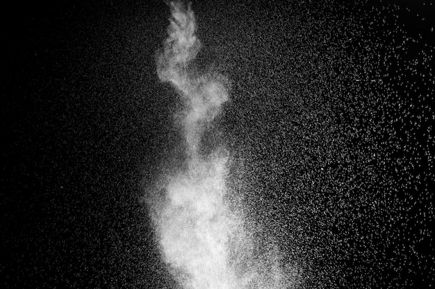 Foto krullende witte stoom die opstijgt en opspattend water verspreidt in verschillende richtingen geïsoleerd op een zwarte achtergrond om te bedekken