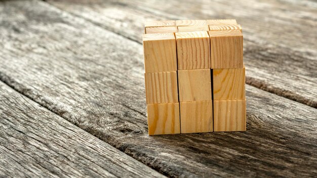 Kubus samengesteld uit 27 kleinere houten kubussen die op gestructureerde houten planken staan