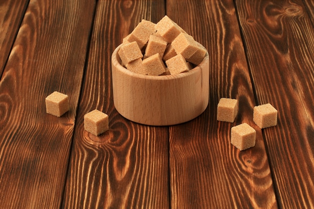 Kubussen van witte en bruine suiker, houten kom op houten tafel. kopieer ruimte.