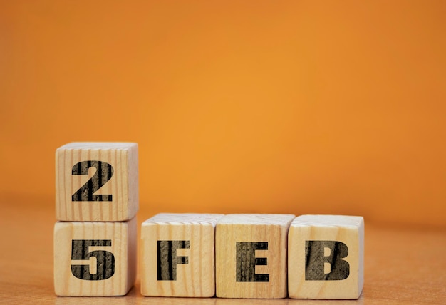 Kubusvormkalender voor 25 februari op houten oppervlak met lege ruimte voor tekst nieuwjaar Houten kalender met datum Februari kubuskalender op houten oppervlak met kopieerruimte