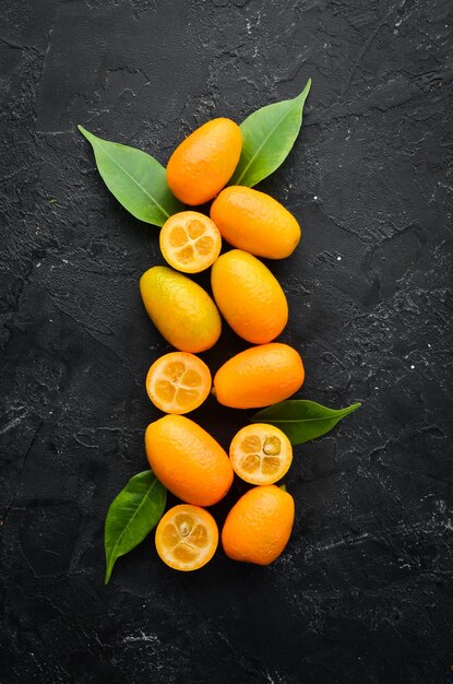 Kumquat on a black stone background. Citrus fruits. Top view. Free space for your text.