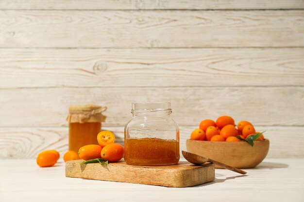 Kumquat and jam in jars on wooden background space for text