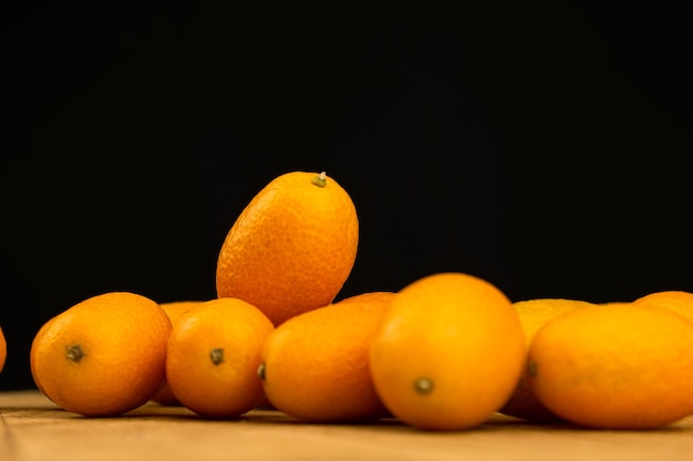 Kumquat, verse citrusvruchten op een zwarte achtergrondgeluid. Cumquat, gezonde voeding, rauw dieet concept. Ruimtefoto kopiëren