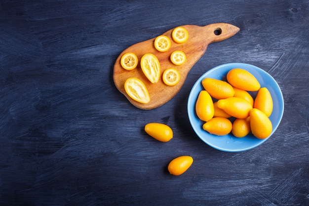 Kumquats in een blauwe plaat op zwart hout