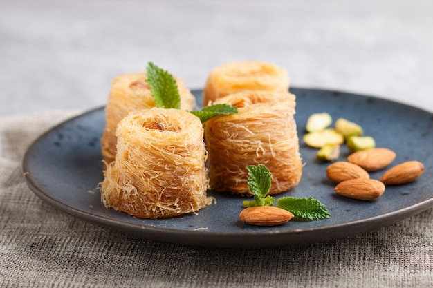 Kunafa, traditional arabic sweets in blue ceramic plate close up.