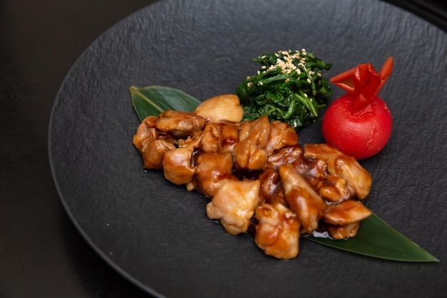 Цыпленок Кунг Пао или Гонг Бао Цзи Дин на фоне темного сланца Сычуань Кунг Пао - блюдо китайской кухни с куриным мясом, перцем чили, арахисовым соусом и луком