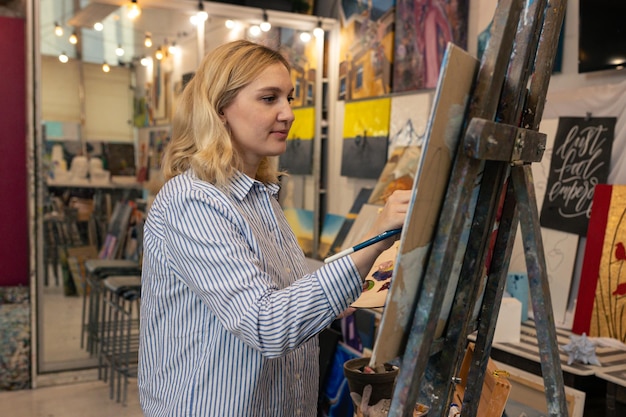 Kunst en cultuur Portret van een jonge vrouw die in het atelier een schilderij aan het schilderen is