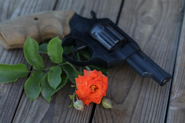 Foto kunst foto. vintage stilleven met pistool en roos op houten achtergrond