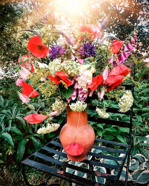 Kunst van het schikken van bloemen Helder romantisch boeket van lentebloemen op de achtergrond van de tuin In compositie klaproos vingerhoedskruid hortensia allium campanula peterselie en pastinaak bloemen