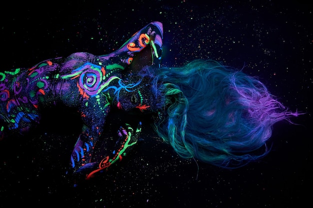 Kunst vrouw lichaam kunst op het lichaam dansen in ultraviolet licht. Heldere abstracte tekeningen op de neonkleur van het meisjeslichaam