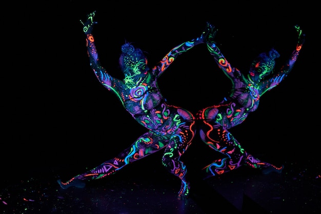 Kunst vrouw lichaam kunst op het lichaam dansen in ultraviolet licht. Heldere abstracte tekeningen op de neonkleur van het vrouwenlichaam