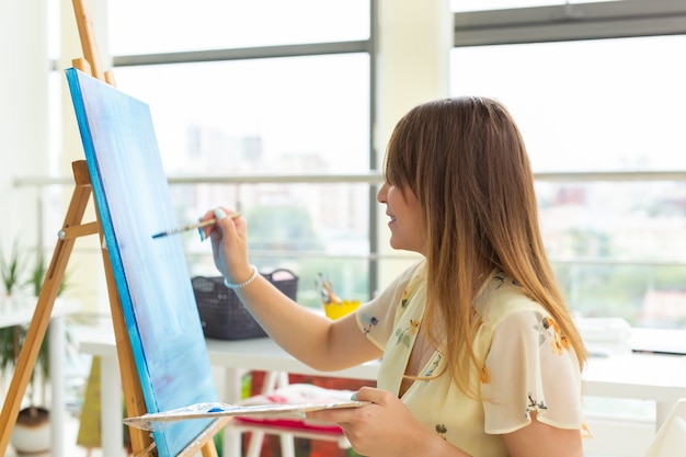 Kunstacademie, kunstacademie, onderwijs voor een groep jonge studenten. Gelukkig jonge vrouw die lacht, meisje leren schilderen.