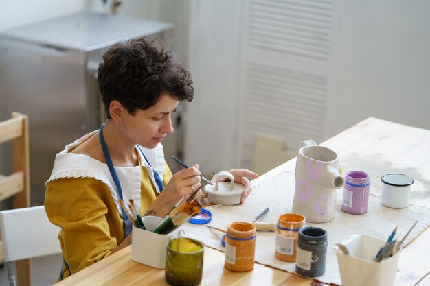 Foto kunstbezetting jonge vrouw studeert keramiek na het werk om een klein bedrijf te starten met een aardewerkstudio