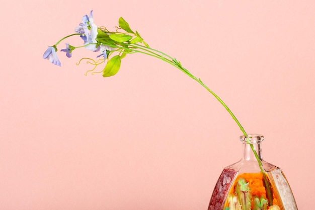 Kunstbloem in handbeschilderde fles op perzik