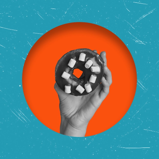 Foto kunstcollage hand met een donut in een oranje cirkel en op een blauwe achtergrond