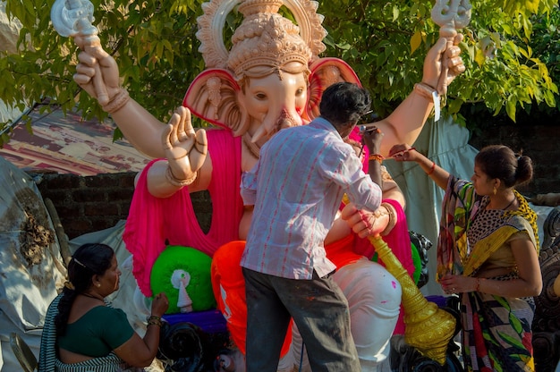 Kunstenaar die een standbeeld maakt en de laatste hand legt aan een idool van de hindoegod Lord Ganesha in een workshop van een kunstenaar voor Ganesha-festival