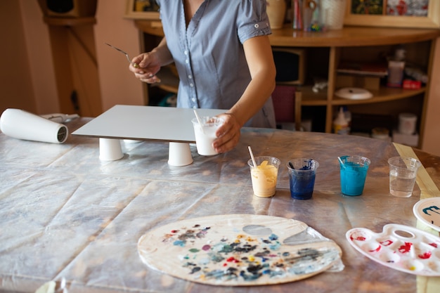 Kunstenaar maakt met behulp van verf een modern interieurbeeld, ze werkt in haar atelier. Geluk en creativiteit. Interieur ontwerp. Thuis vrije tijd. Masterclass.