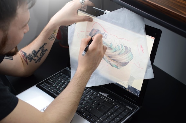 Kunstenaar omcirkelt penschets van een tatoeage op het bureaublad
