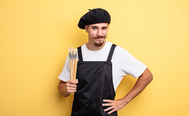 Kunstenaar schilder vrolijk glimlachend met een hand op de heup en zelfverzekerd