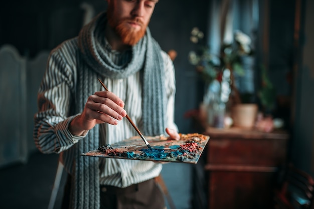 Kunstenaar schildert kleuren op het palet, art studio