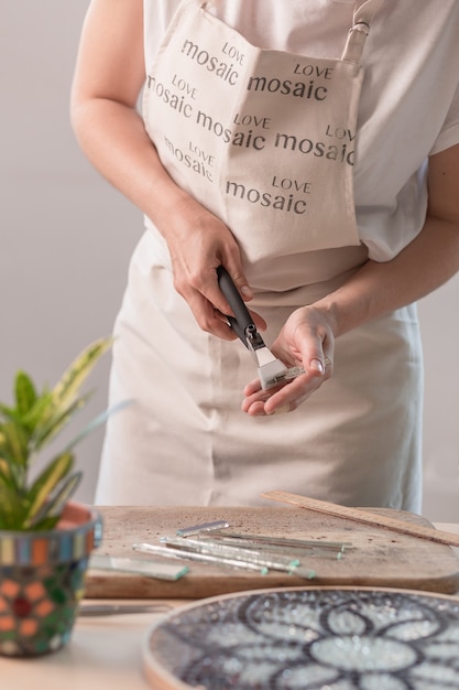 Kunstenaar snijdt vellen glas-in-lood in kleine mozaïekvierkantjes. Detailopname