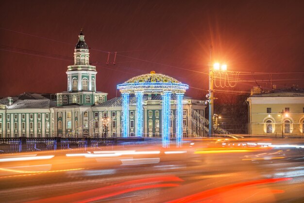 Кунсткамера и новогоднее оформление Дворцового моста в Санкт-Петербурге в свете ночных огней автомобилей