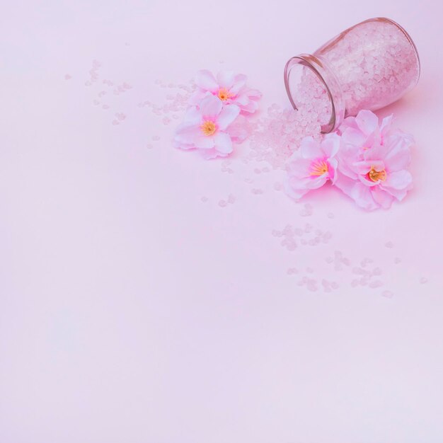 Foto kunstmatige bloemen gemorst zout uit pot roze achtergrond