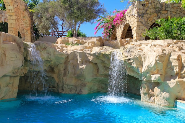 Kunstmatige waterval in zwembad, zonnige dag