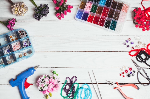 Kunststof bessen, bloemen, kralen en instrumenten voor het maken van handgemaakte decoraties en sieraden. Bovenaanzicht met kopieerruimte