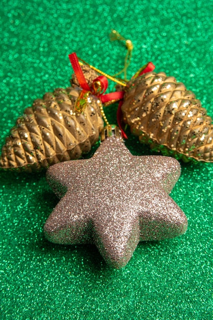 Kunststof kerst dennenappels en ster op groen oppervlak met glitter. selectieve aandacht.