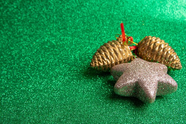 Kunststof kerst dennenappels en ster op groen oppervlak met glitter. selectieve aandacht.