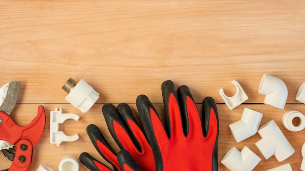 Kunststof pijp snijgereedschap en handschoenen op houten ondergrond met advertentieruimte.