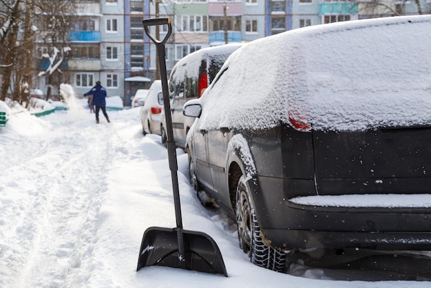 Kunststof sneeuwschop voor besneeuwde auto op zonnige winterochtend